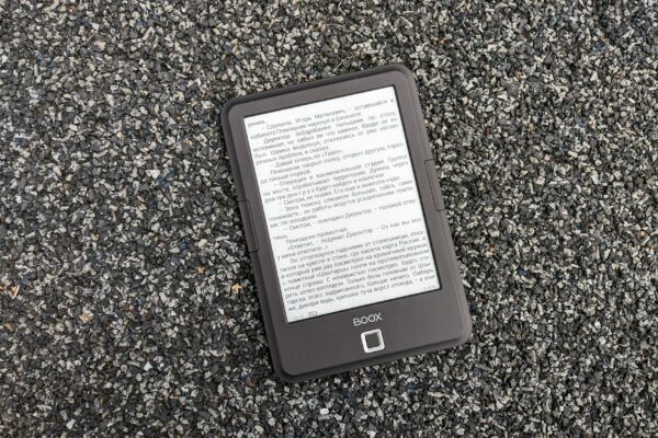 Digital BOOX e-book reader placed on a textured gravel surface, offering a tech contrast.