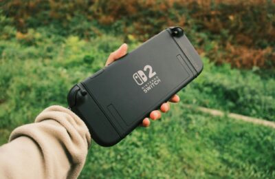 Person holding a Nintendo Switch in a natural outdoor setting, perfect for on-the-go gaming.