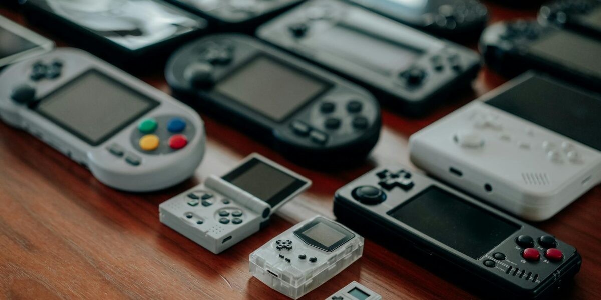 Collection of diverse retro handheld gaming consoles on a wooden surface, showcasing classic designs and nostalgia.