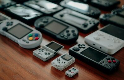 Collection of diverse retro handheld gaming consoles on a wooden surface, showcasing classic designs and nostalgia.