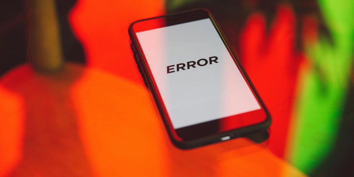 A smartphone displaying an 'ERROR' message surrounded by vibrant red and green reflections indoors.