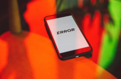 A smartphone displaying an 'ERROR' message surrounded by vibrant red and green reflections indoors.