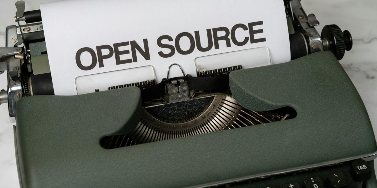 Close-up of a vintage typewriter with 'Open Source' typed on paper, conveying creativity.