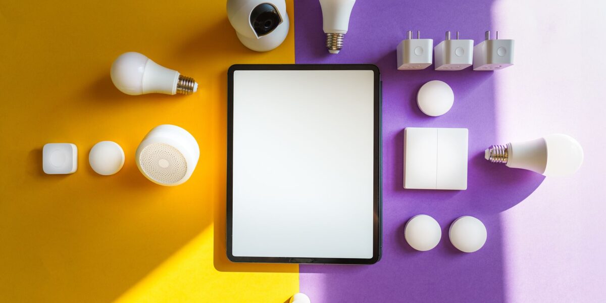 Top view of smart home devices and tablet on split yellow and purple background.