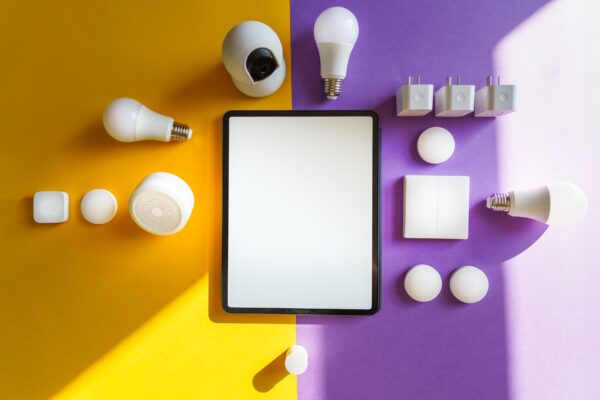 Top view of smart home devices and tablet on split yellow and purple background.