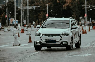 White car racing during urban rally and driving down paved street in daylight