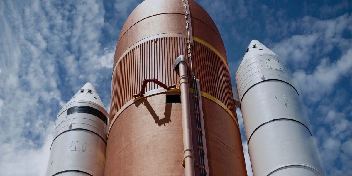 Dramatic view of rocket boosters against a bright blue sky, showcasing aerospace technology.