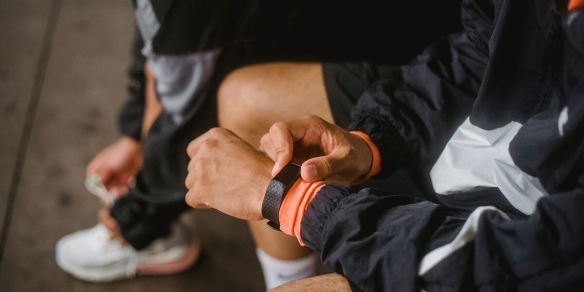 Close-up of a man in athletic wear adjusting a smartwatch, showcasing fitness and technology integration.