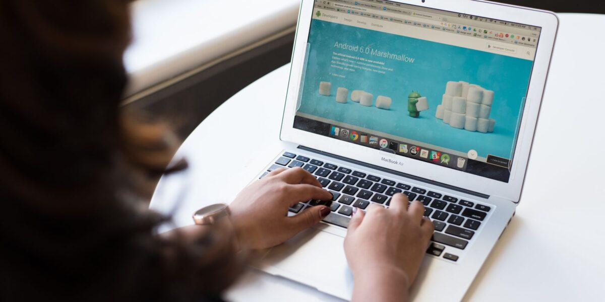 Businesswoman working on laptop with Android 6.0 Marshmallow webpage open.