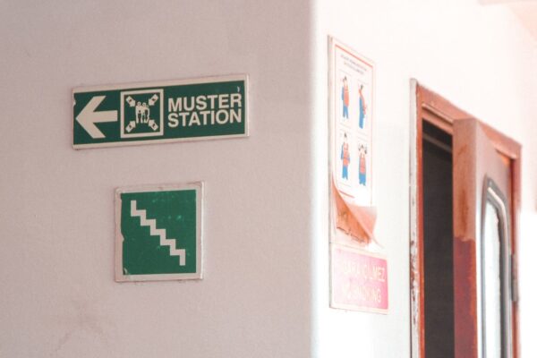 Emergency muster station signs indoors with directional and safety instructions.