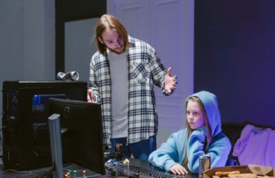 A father scolds his daughter playing video games on a computer, creating a tense moment.