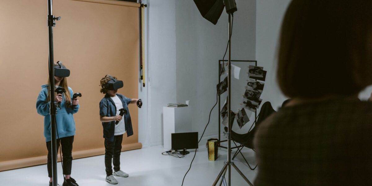Two kids experience virtual reality gaming in a professional studio setting with VR headsets and controllers.