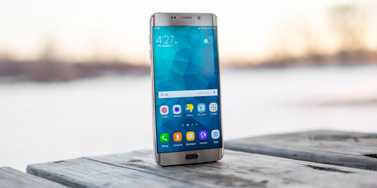 Samsung smartphone placed on a wooden surface outdoors during sunset.