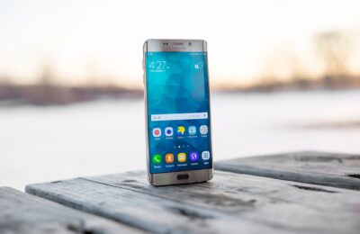 Samsung smartphone placed on a wooden surface outdoors during sunset.