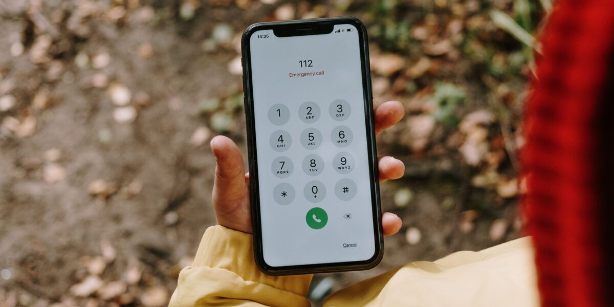 Close-up of a smartphone displaying emergency number 112 outdoors.