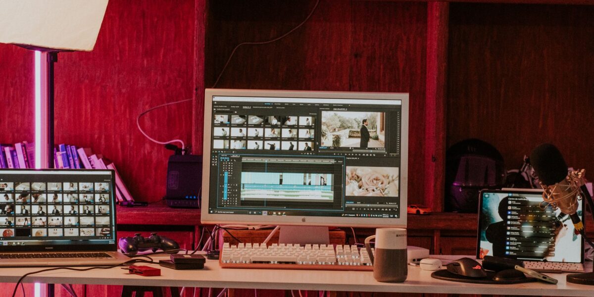 A professional video editing workspace featuring monitors, keyboard, and microphones in a studio setting.