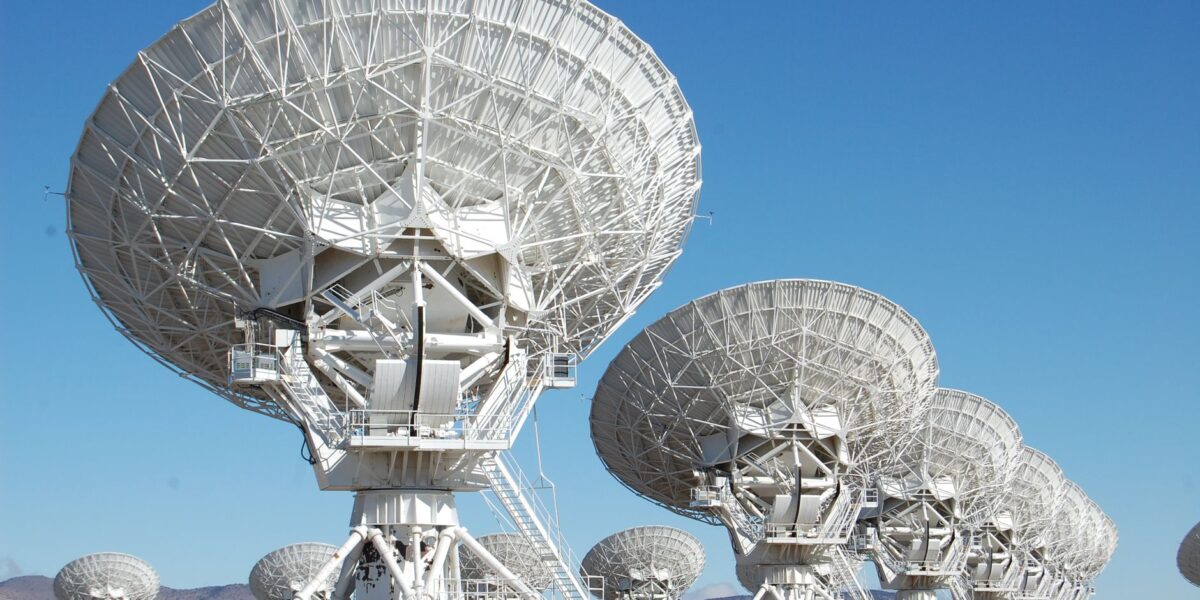 Array of radio telescopes at the Very Large Array in New Mexico under a clear blue sky.