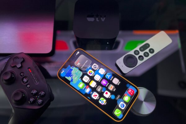 Stylish home entertainment setup featuring an iPhone, Apple TV, and gaming controller on a dark surface.