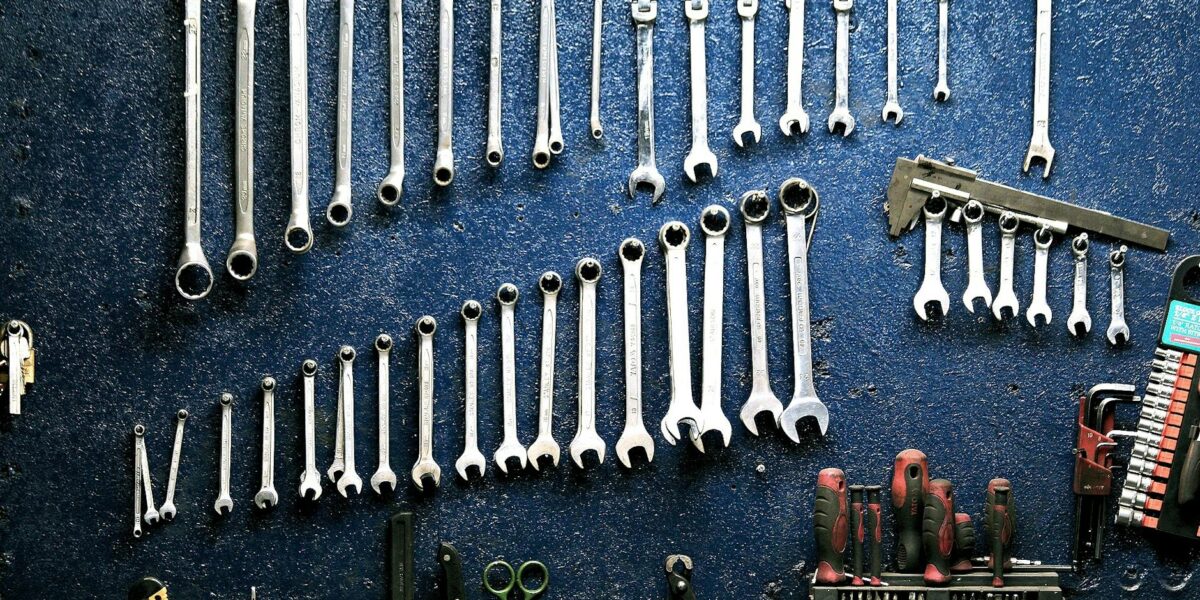 Neatly arranged wrenches and tools on a workshop wall, ideal for mechanics.