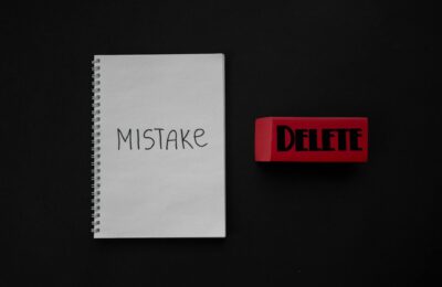 Notebook labeled 'Mistake' next to a red delete eraser on a dark background.