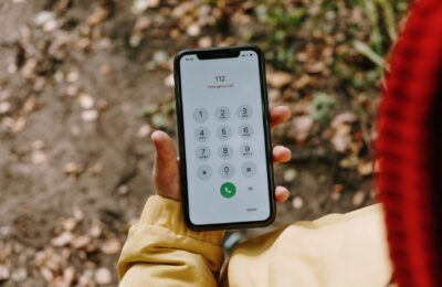 Close-up of a smartphone displaying emergency number 112 outdoors.