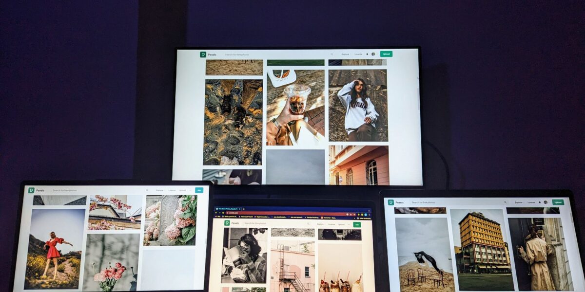A high-tech workspace featuring three laptops and a monitor with various images displayed, highlighting technology and digital art.