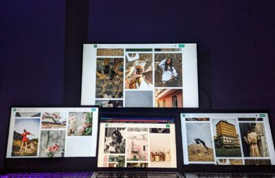 A high-tech workspace featuring three laptops and a monitor with various images displayed, highlighting technology and digital art.