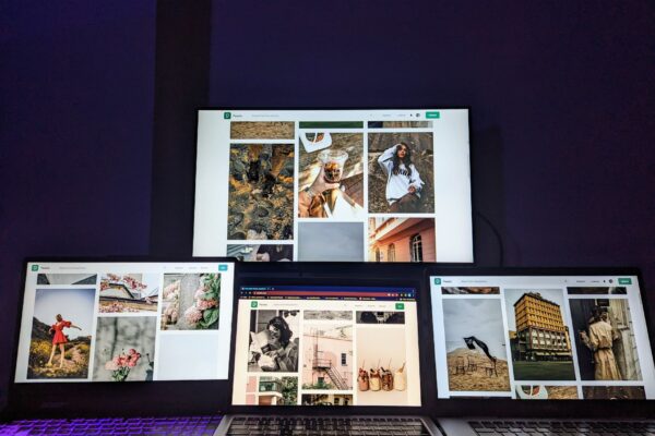 A high-tech workspace featuring three laptops and a monitor with various images displayed, highlighting technology and digital art.