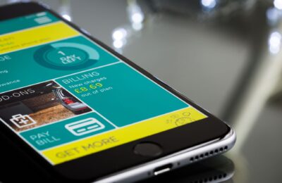 Close-up of a smartphone displaying a billing app interface on a reflective surface.