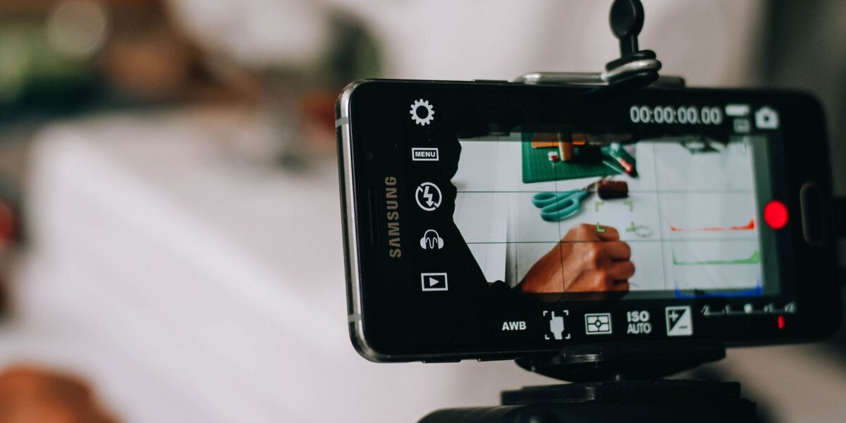 Smartphone on tripod capturing person writing on paper, showing content creation process.