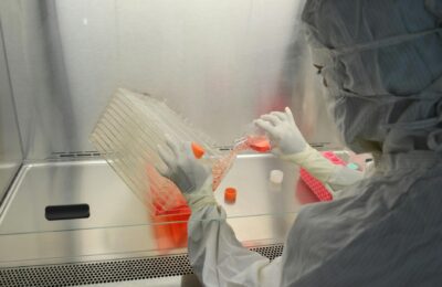 A scientist in full protective gear working in a laboratory on research with cell cultures.