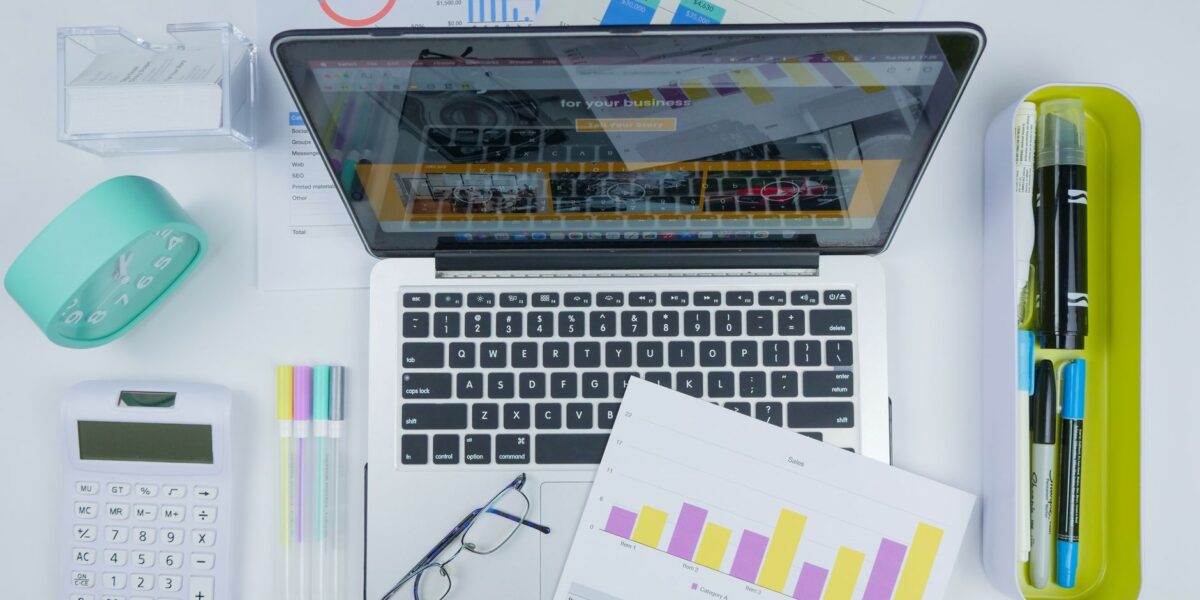Top view of a creative workspace featuring a laptop, charts, and office stationery.