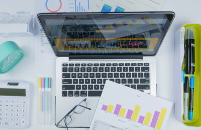 Top view of a creative workspace featuring a laptop, charts, and office stationery.