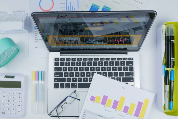 Top view of a creative workspace featuring a laptop, charts, and office stationery.