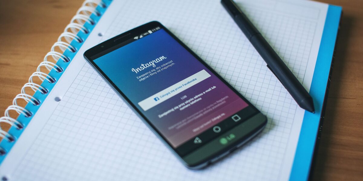 A smartphone displaying Instagram on a notepad with a pen, symbolizing social media and productivity.