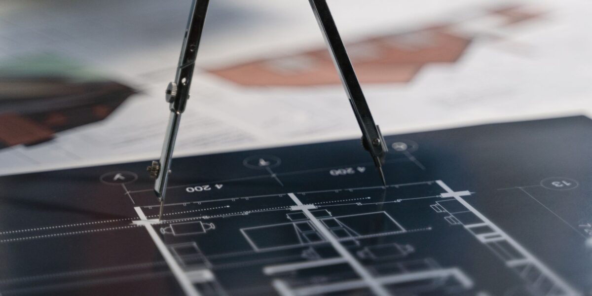 A compass on architectural blueprints, showcasing planning and measurement details.