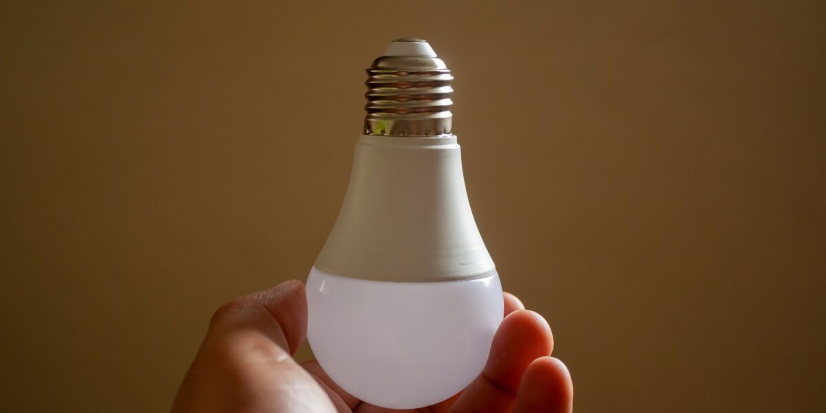 Close-up of a hand holding an energy-efficient LED bulb, emphasizing sustainability and innovation.