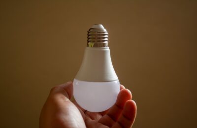 Close-up of a hand holding an energy-efficient LED bulb, emphasizing sustainability and innovation.