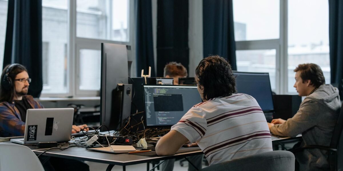 Team of developers working together on computers in a modern tech office.