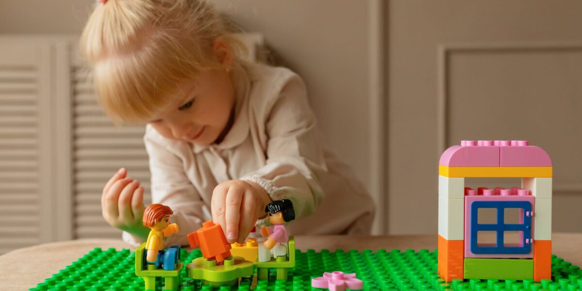 A young girl engaging creatively with colorful plastic building blocks on a table indoors.