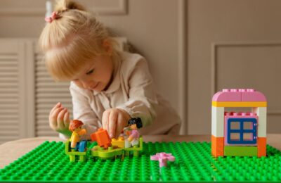 A young girl engaging creatively with colorful plastic building blocks on a table indoors.