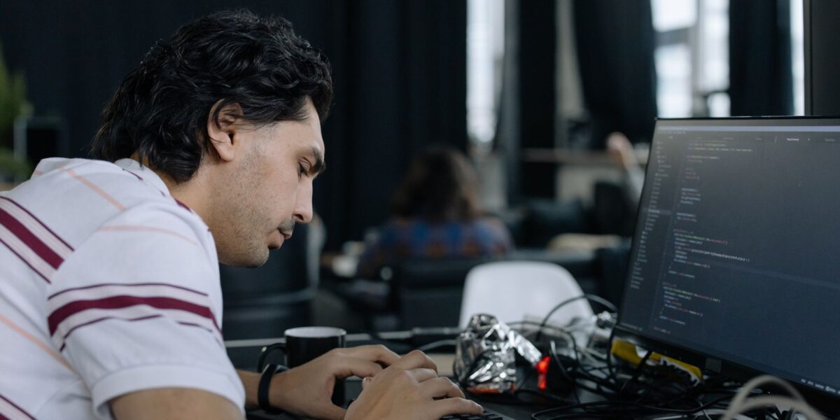 A coder intensely typing at a workstation in a contemporary office setup.