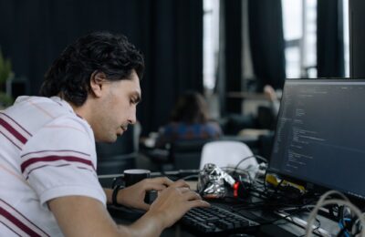 A coder intensely typing at a workstation in a contemporary office setup.