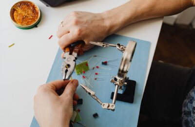 Close-up view of hands using tools to assemble electronic components with precision on a desk.