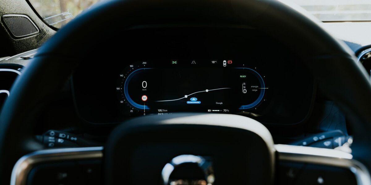 Close-up of a Volvo car steering wheel with digital dashboard display, showcasing modern automotive technology.
