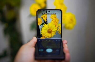 A smartphone capturing vivid yellow flowers, showcasing technology and nature interaction.