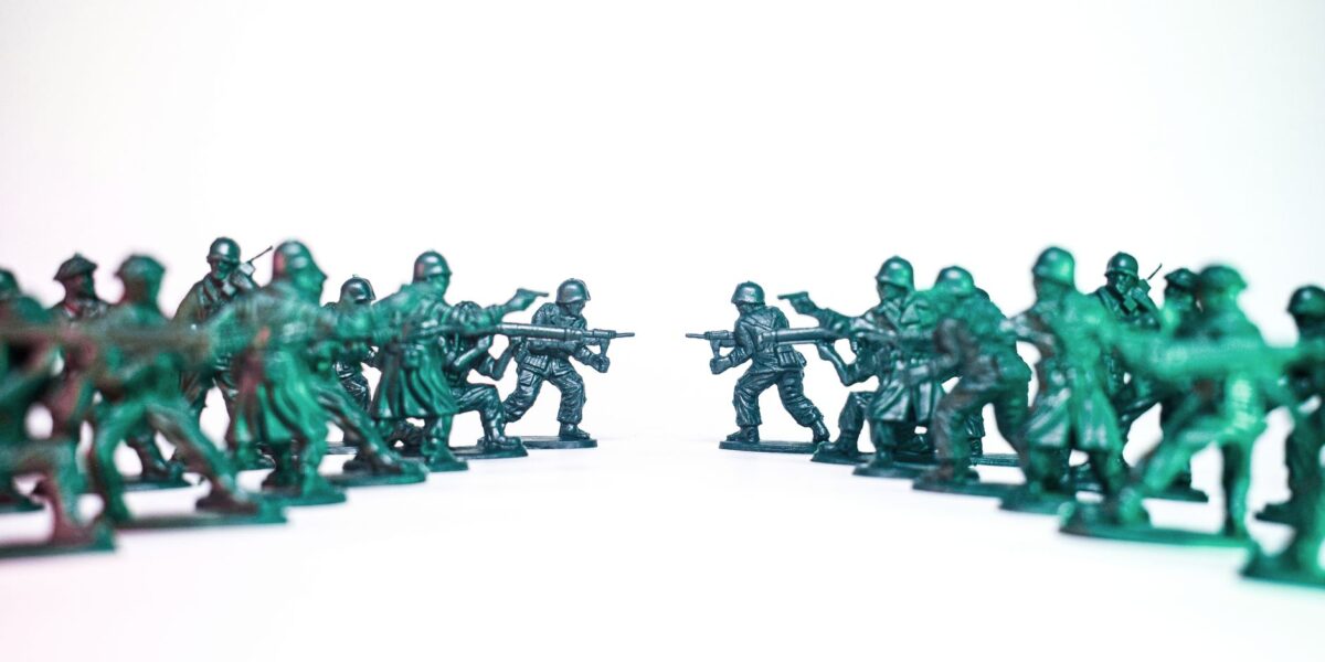 Green toy soldiers facing off on a white background, symbolic of conflict and strategy.