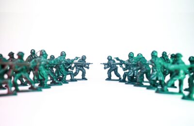 Green toy soldiers facing off on a white background, symbolic of conflict and strategy.