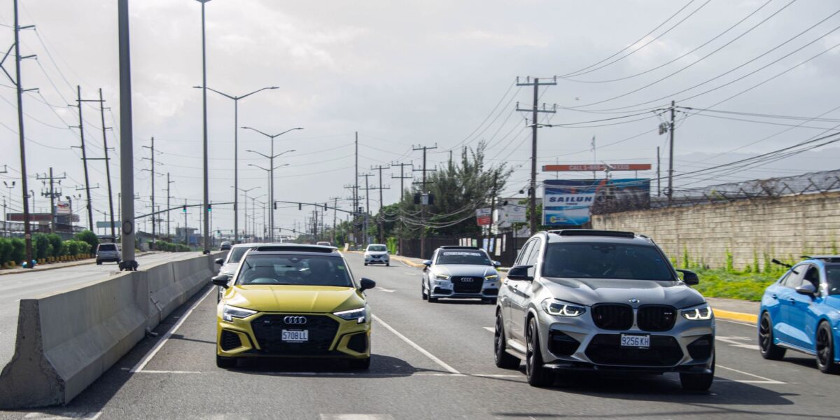 A variety of cars on a busy highway in Jamaica, showcasing urban travel.