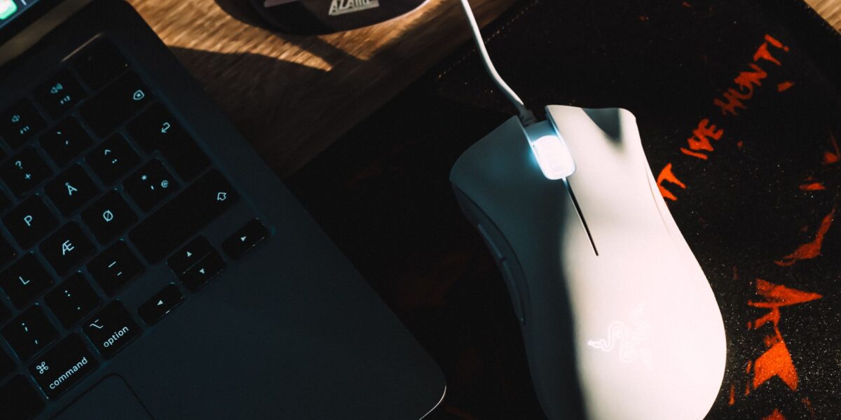 Stylish workspace setup featuring a gaming mouse and laptop with dramatic lighting.